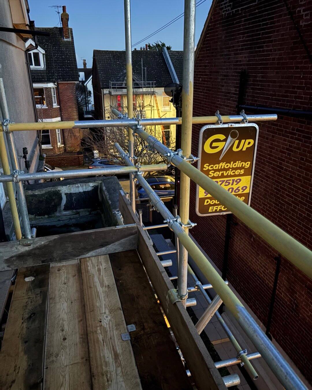 Golden hour shot of scaffold deck and GUP sign against a brick wall