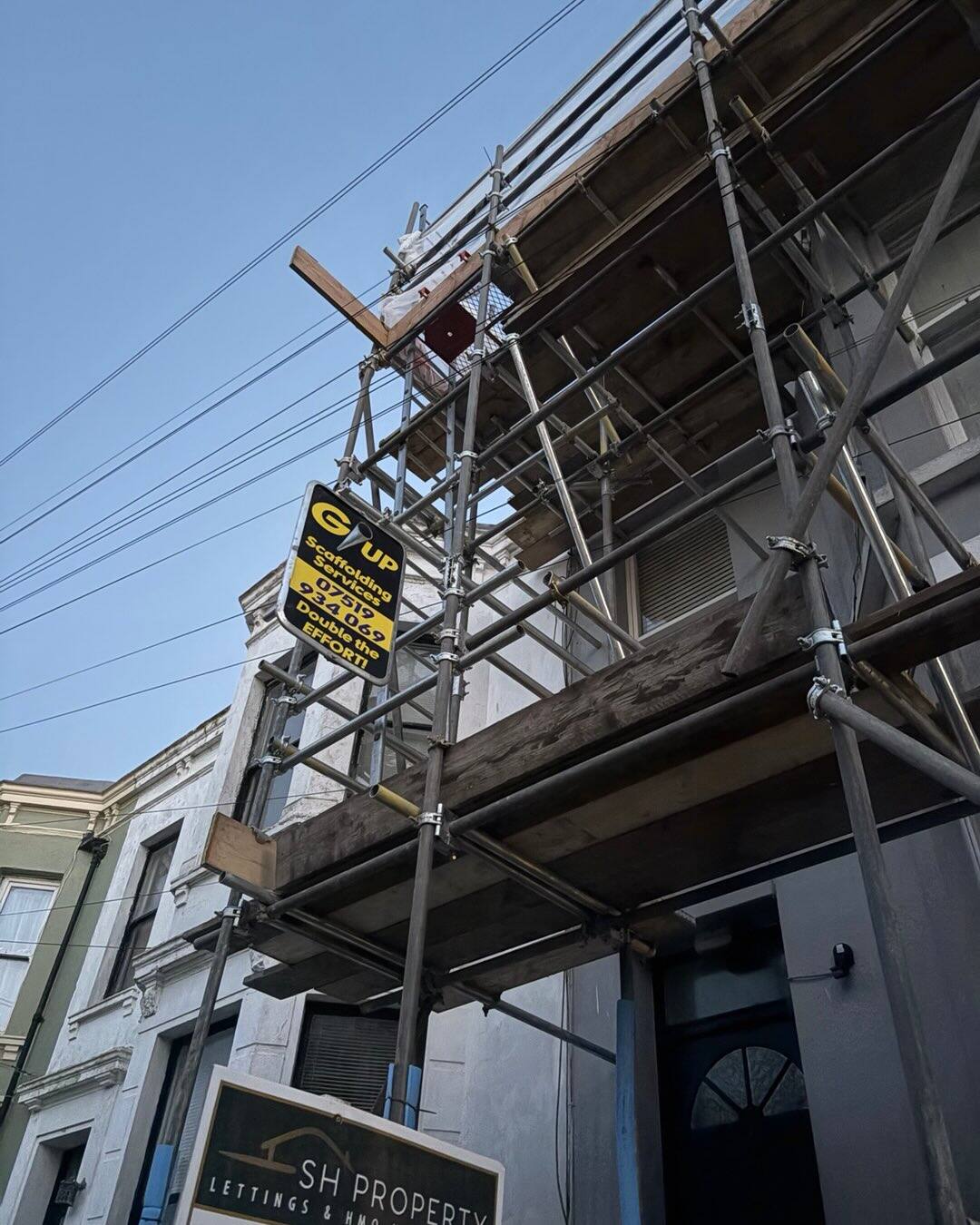Cantilevered scaffold over a period terrace shopfront with letting agency signage
